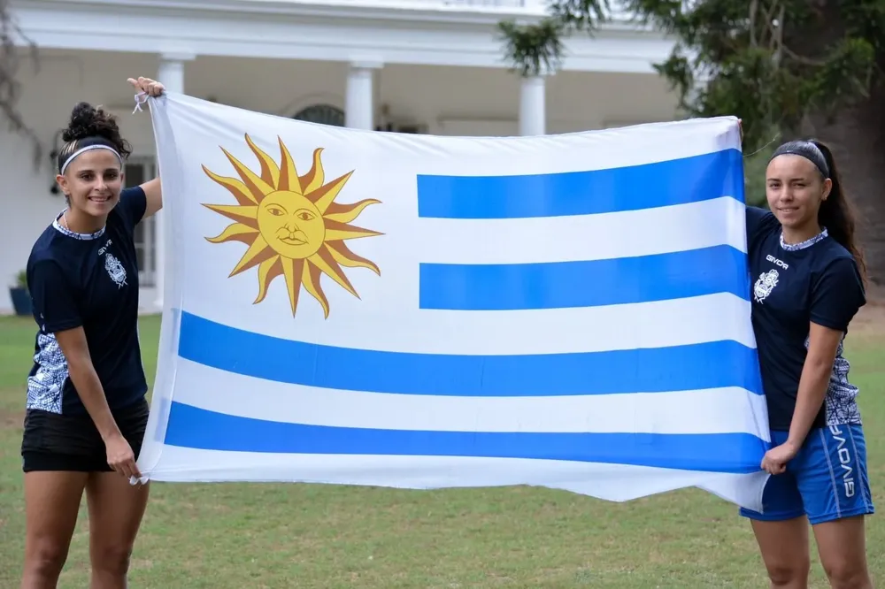 Camila Santos y Sharon López con la bandera de Uruguay y la camiseta de Gimnasia