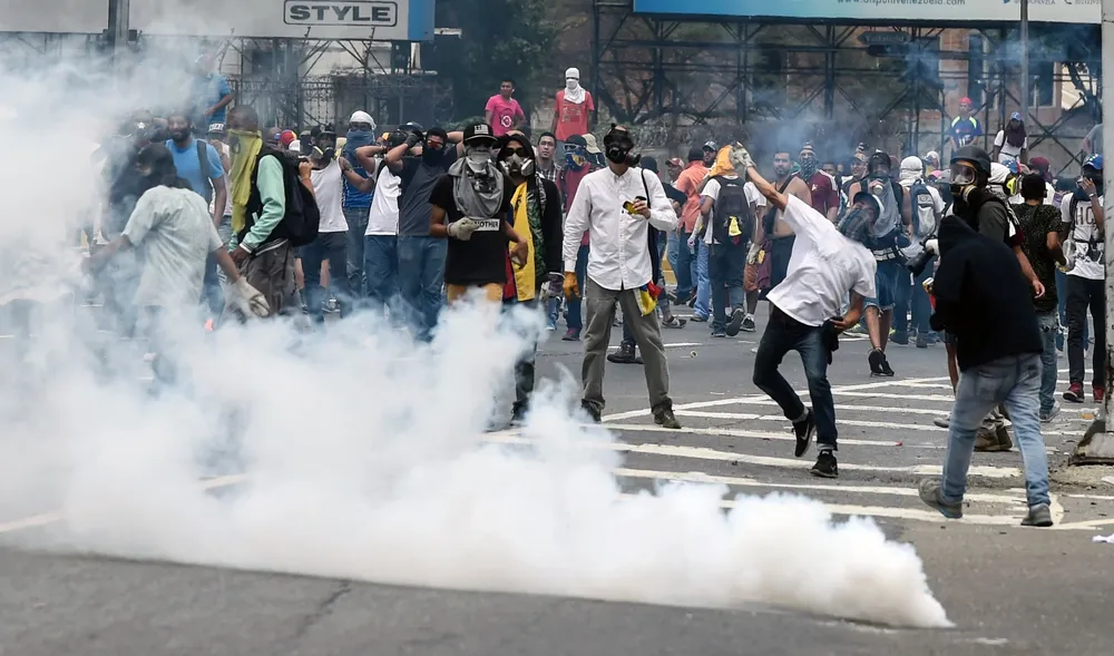 Demonstrators clash with the riot police during a protest against Venezuelan President Nicolas Maduro, in Caracas on April 20, 2017. Venezuelan riot police fired tear gas Thursday at groups of protesters seeking to oust President Nicolas Maduro, who have vowed new mass marches after a day of deadly unrest. Police in western Caracas broke up scores of opposition protesters trying to join a larger march, though there was no immediate repeat of Wednesdays violent clashes, which left three people dead. / AFP / JUAN BARRETO