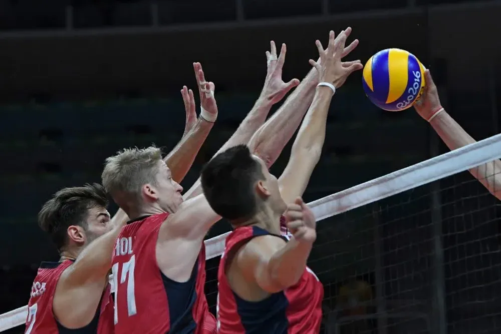 Tres deportistas estadounidenses buscan detener una jugada italiana durante un partido de voleyball
