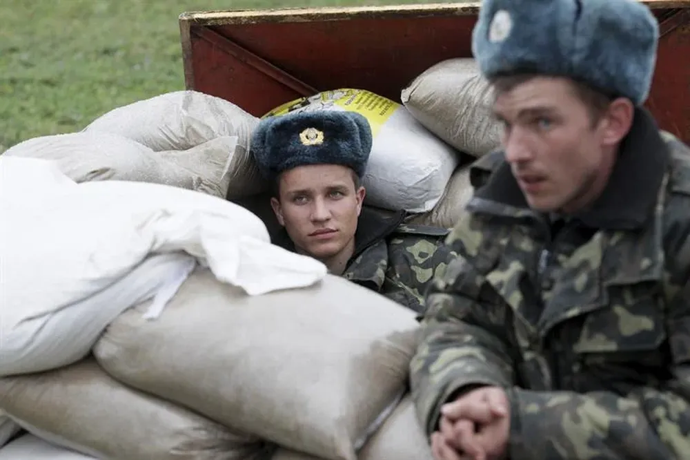 Ucrania- Soldados permanecen sentados mientras hombres armados bloquean la entrada de la base aérea de Bilbek