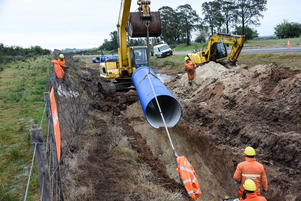 Retroexcavadora levanta caño para colocarlo al costado de la ruta