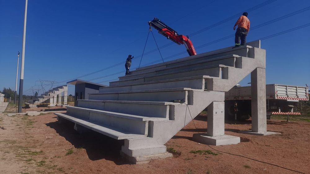 Al fondo se ve una tribuna ya colocada en la Ciudad Deportiva Néstor "Tito" Goncálves de Peñarol, mientras los obreros colocan una nueva Al fondo se ve una tribuna ya colocada en la Ciudad Deportiva Néstor "Tito" Goncálves de Peñarol, mientras los obreros colocan una nueva