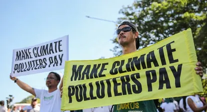 Manifestantes portan pancartas reclamando que los países con mayores emisiones de gases de efecto invernadero aporten fondos para evitar el calentamiento del planeta.
