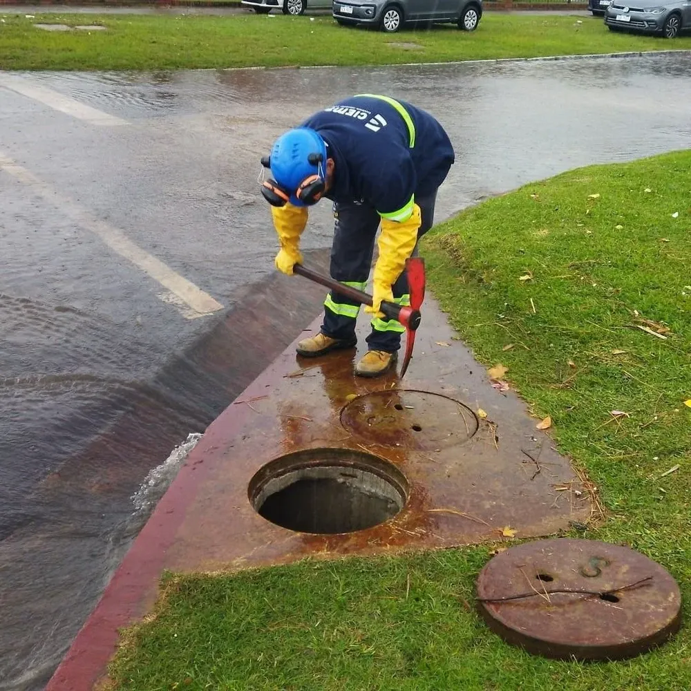 Trabajador municipal limpiando boca de tormenta