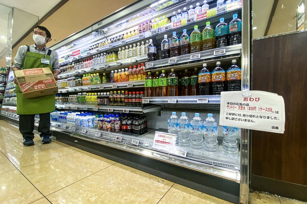 Un trabajador traslada botellas de agua con un cartel escrito el agua embotellada está racionada, con una tapa de una caja (seis botellas) por cada cliente, en un supermercado en el distrito Sumida de Tokio en agosto. Autoridades de Japón instan al público a evitar el acaparamiento, ya que la ansiedad por un posible megaterremoto ha provocado un aumento en la demanda de kits de desastre y artículos de primera necesidad.