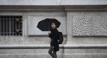 Una mujer se protege de la lluvia bajo su paraguas.