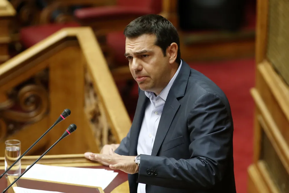 Greek Prime Minister Alexis Tsipras gestures as he speaks at the podium during an overnight parliamentary debate in Athens on August 14, 2015. Greeces parliament on August 14 approved the countrys third international bailout after an all-night debate, hours ahead of a critical meeting by European finance ministers. AFP PHOTO/ PANAYIOTIS TZAMAROS