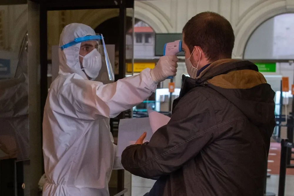 Un enfermero toma la temperatura a una persona en la entrada del puerto de Montevideo
