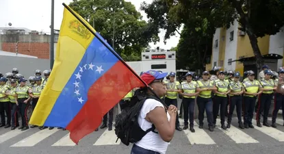 Una manifestante pasa con la bandera de Venezuela frente al cordón policial que dispuso el gobierno.
