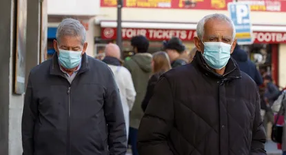 Dos hombres usan mascarilla mientras andan por la calle en Madrid.