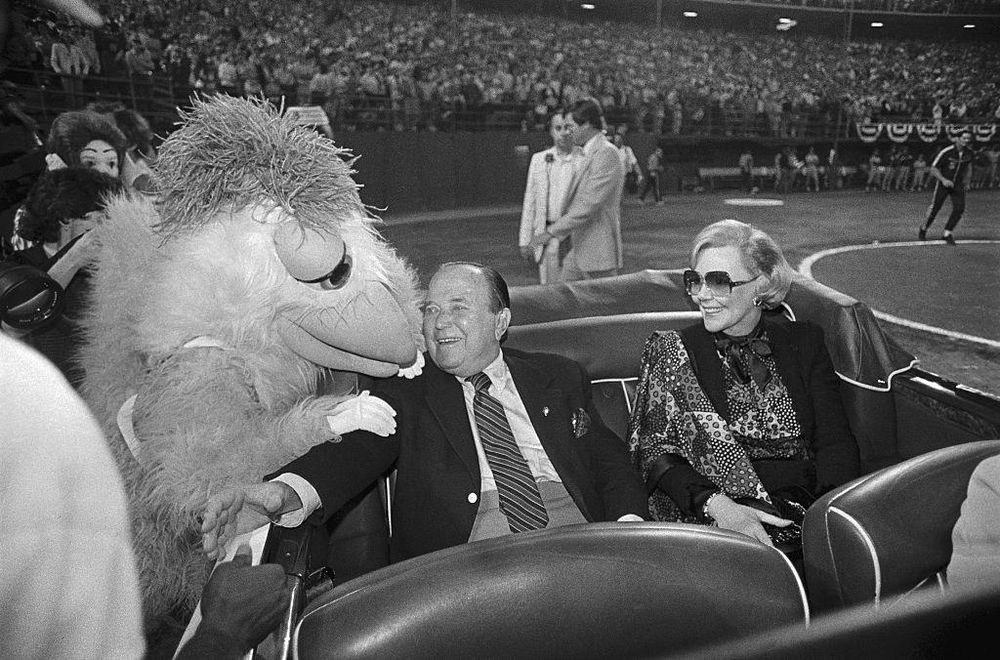 Joan con Ray Kroc, cuando él era dueño del equipo profesional de béisbol San Diego Padres y la mascota lo saludó en honor a su 80º cumpleaños en el Estadio Jack Murphy.