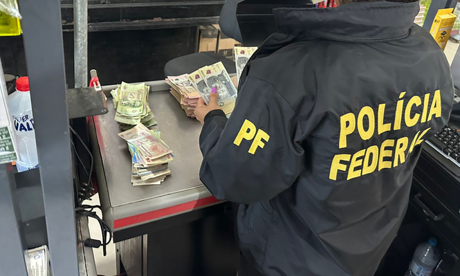 Oficial de la Policía Federal de Brasil con parte del dinero incautado a la banda
