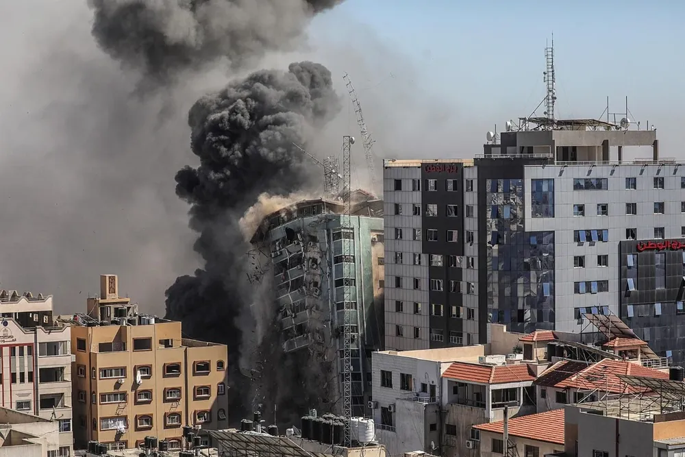 Una columna de humo asciende de una torre de 14 plantas en la ciudad de Gaza, sede de la agencia de noticias estadounidense AP, la cadena de noticias Al Jazeera y otros medios internacionales