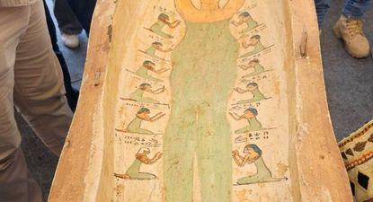 La tapa del sarcófago muestra a una mujer de piel amarilla, vestida con ropa verde y un tocado azul, similar al peinado de Marge
