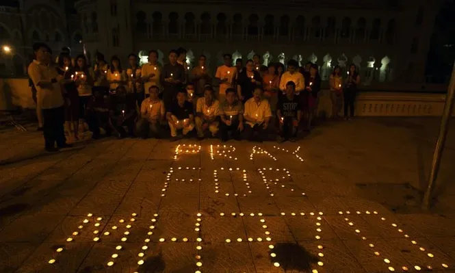 Malasia- Varias personas posan frente a un conjunto de velas que conforman la frase Rezar por MH370