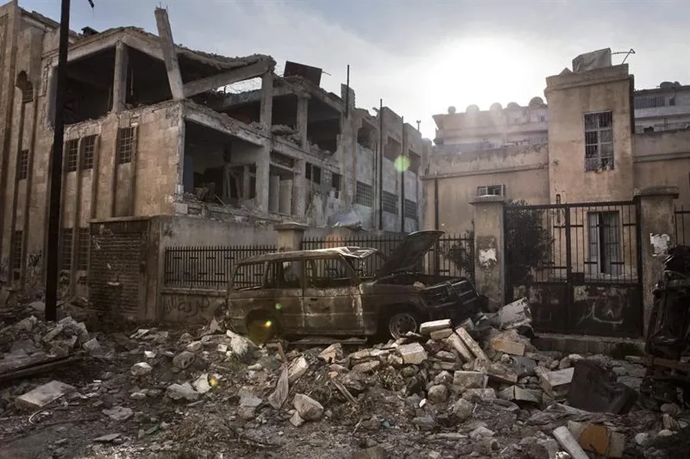 Siria- Vista de un coche y unos edificios destruídos en el barrio de Saif Al Dawla en Alepo
