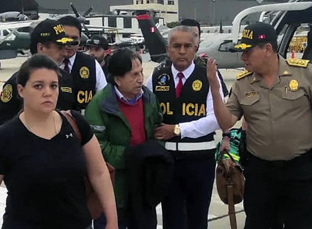 El expresidente Alejandro Toledo es trasladado por autoridades policiales a su arribo a Perú.