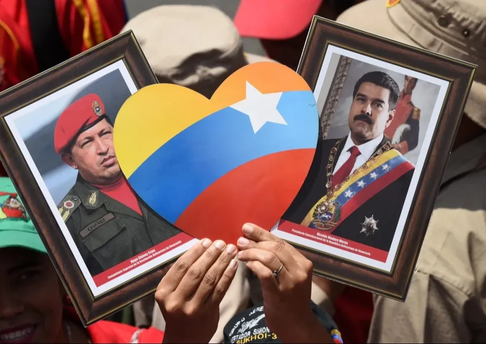 Un asistente al acto de conmemoración del “4F” convocado por el gobierno muestra los retratos de Hugo Chávez y el presidente Maduro.
