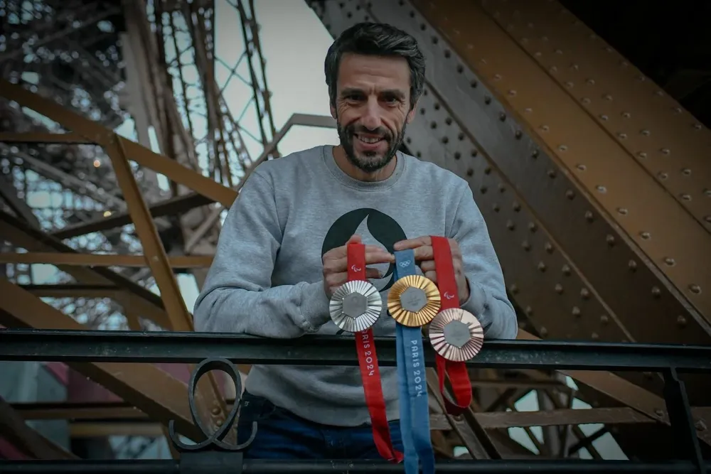 El presidente del comité organizador de los Juegos con las medallas