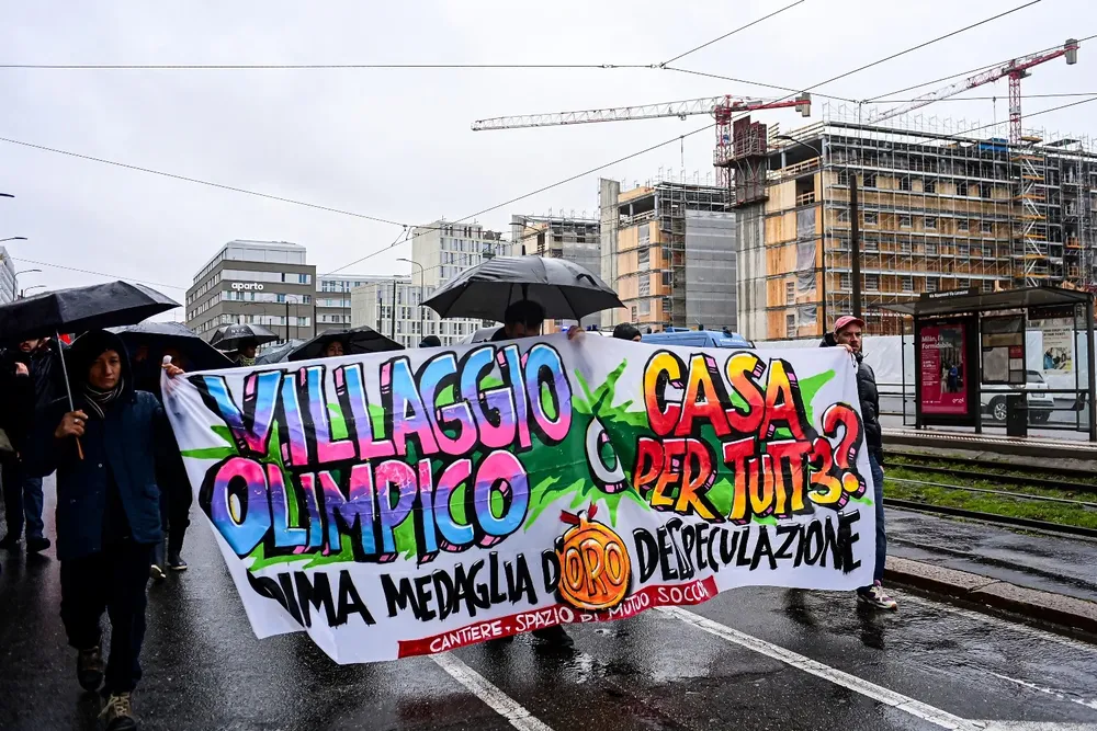 Manifestantes contra los Juegos Olímpicos en Milán-Cortina llevan un cartel con la inscripción “Villa Olímpica o casa para todos”.
