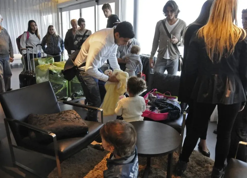 Sala VIP del aeropuerto: Suárez prepara a su hija previo a la salida a Europa tras los partidos con la selección. Coates y Cavani lo miran