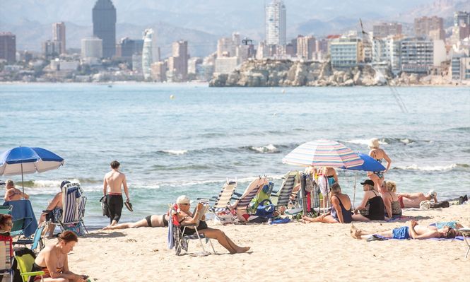 Numerosas personas se bañan y toman el sol en la playa de Poniente, en Benidorm, Alicante.