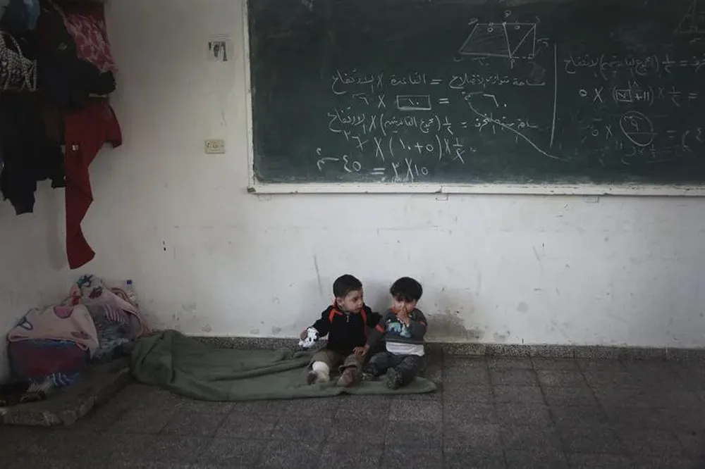 Gaza- Dos niños palestinos que huyeron de sus casas al norte de Gaza esperan en un salón de clases