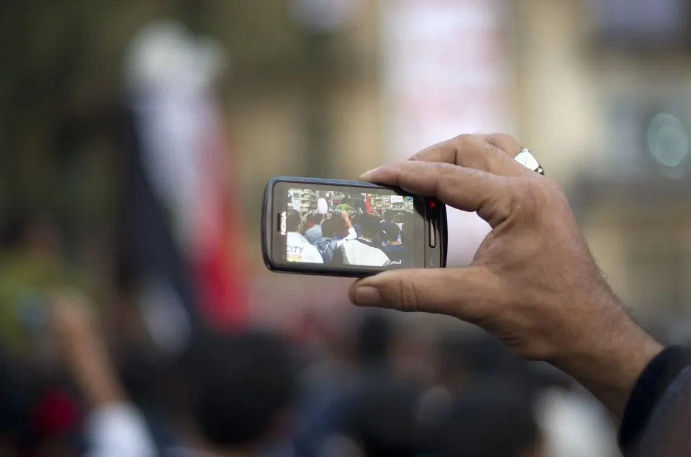 En esta foto de archivo tomada el 24 de noviembre de 2011, un hombre usa su teléfono celular para registrar la actividad de otros manifestantes antigubernamentales durante una manifestación masiva en la plaza Tahrir de El Cairo. Las redes sociales y los teléfonos inteligentes dieron brevemente a los jóvenes manifestantes de la Primavera Árabe una ventaja tecnológica que les permitió derrocar dictaduras envejecidas a medida que su espíritu revolucionario se volvía viral.
