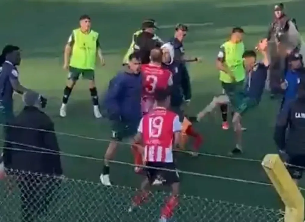 Un jugador de Deportivo Italiano le tira una patada a la cabeza a un rival de Villa Teresa que está en el suelo