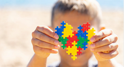 El Observador | Niño sosteniendo un corazón de rompecabezas de colores.