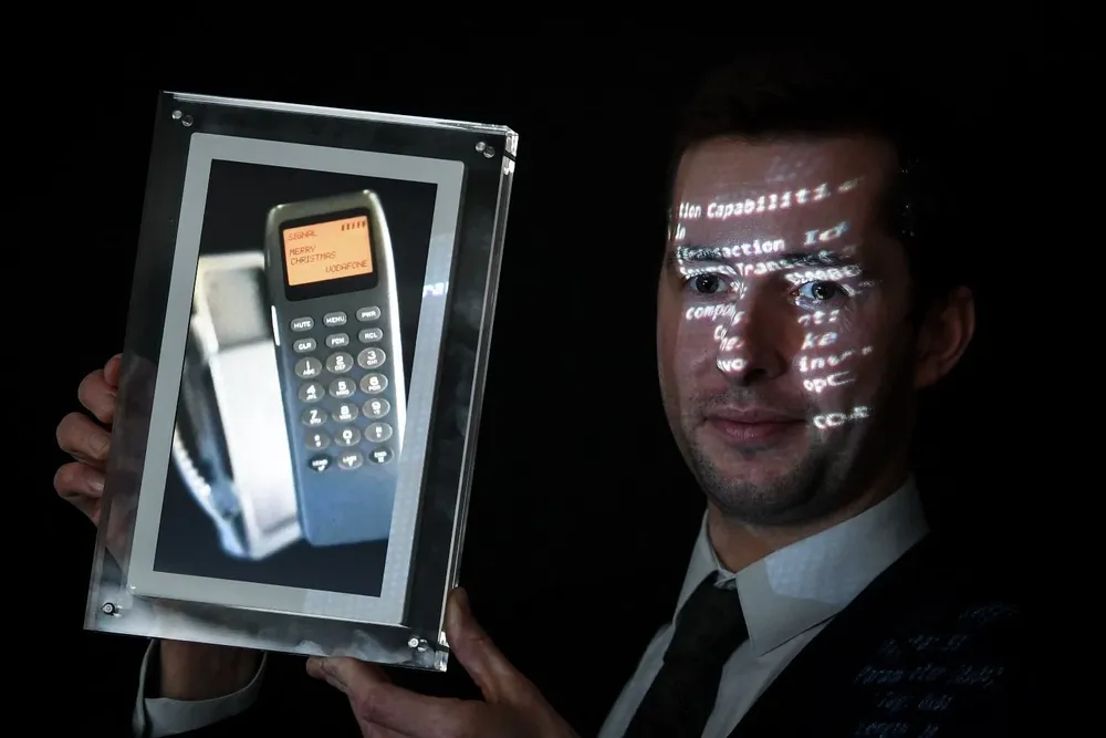 Maximillien Aguttes, gerente de desarrollo de la casa de subastas Aguttes, presenta una pantalla que muestra un teléfono con el primer SMS del mundo.