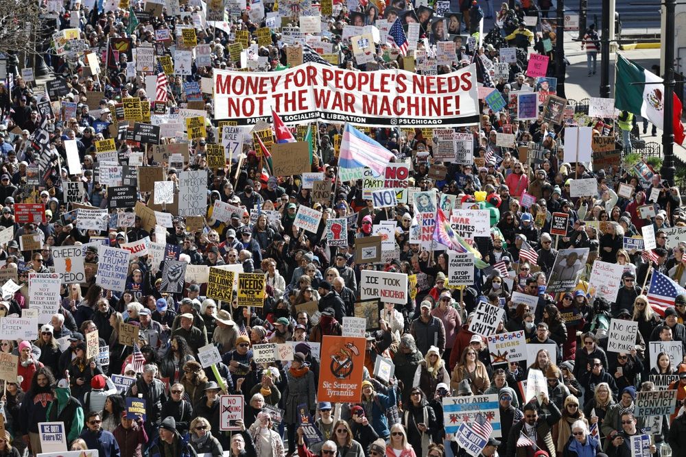 La gente sostiene carteles y banderas en Chicago mientras marchan durante el tercer d&iacute;a de protesta "No Kings" desde que empez&oacute; el ciclo Trump.