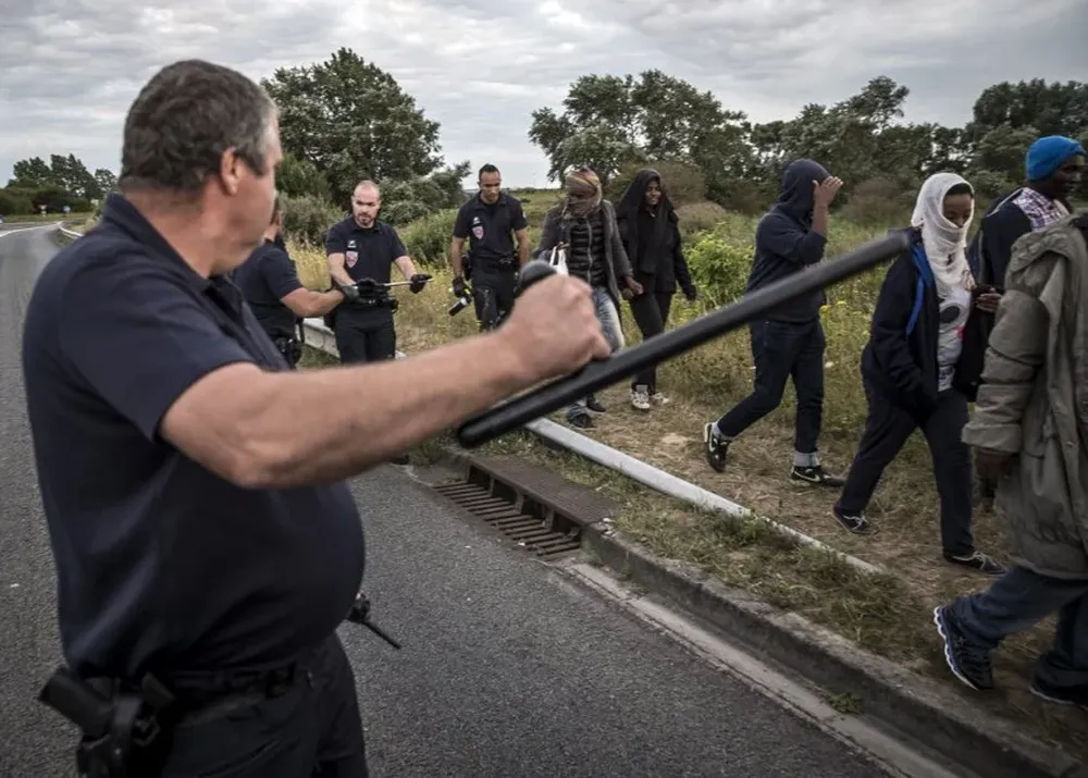 Policías detienen a un grupo de migrantes en Coquelles