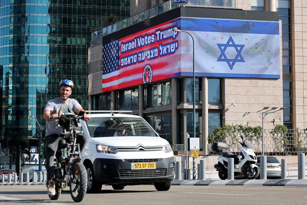 Estadounidenses a punto de elegir quien los presidirá: viajeros conducen por una carretera frente a un cartel con las banderas de Estados Unidos e Israel con un mensaje de apoyo al candidato presidencial estadounidense Donald Trump en Tel Aviv el 30 de octubre de 2024.