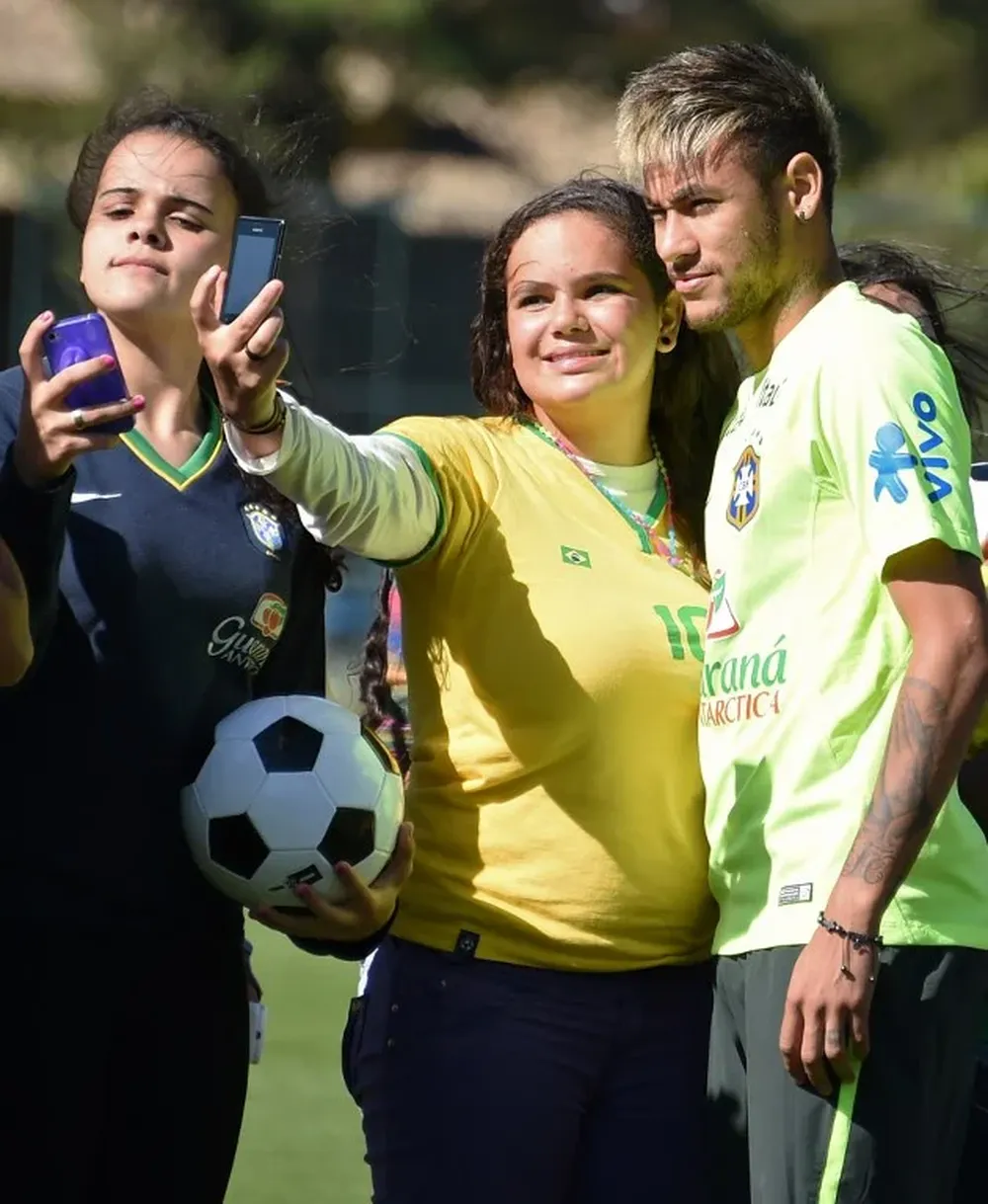 El jugador estrella brasileño Neymar posa para una selfie con una fan previo a un entrenamiento