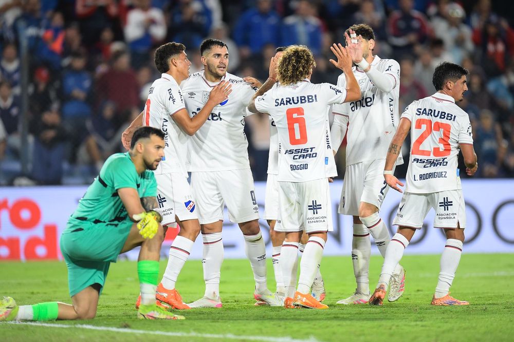 Maximiliano Gómez y sus compañeros de Nacional celebran la victoria ante la desazón del arquero de Cerro Largo, Pedro González, por el Torneo Apertura
