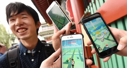 Estudiantes japoneses muestran sus celulares mientras juegan al Pokémon Go