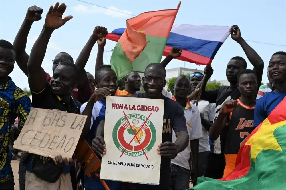 Un pequeño grupo de manifestantes sostienen banderas de Rusia y Burkina Faso mientras protestan contra la CEDEAO.
