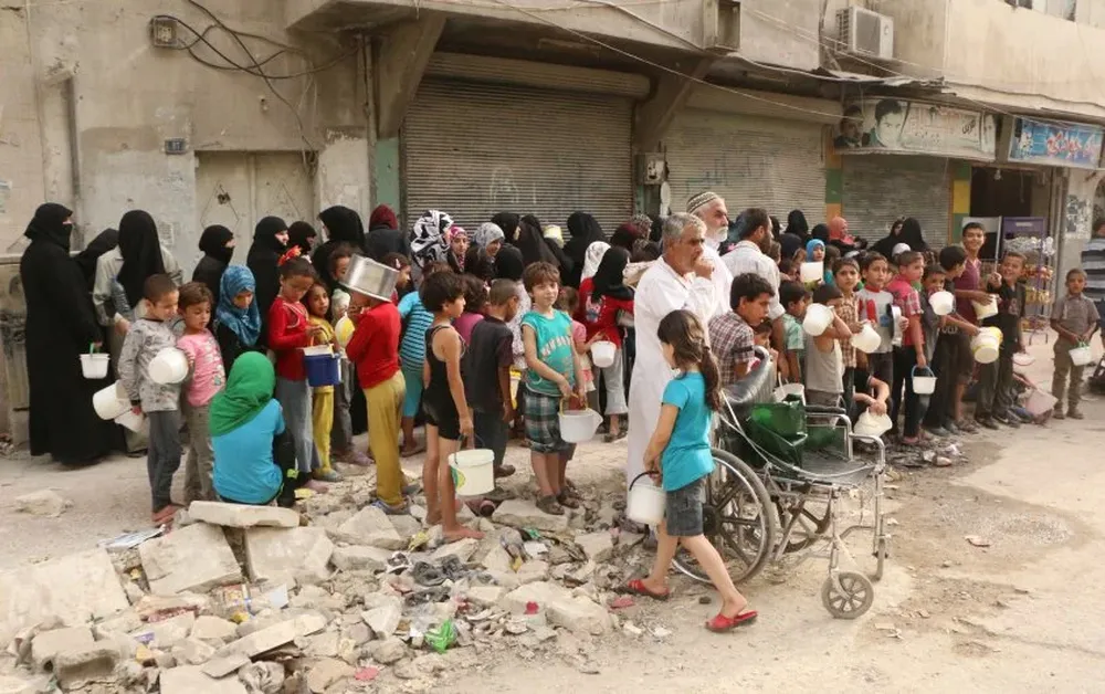 Sirios desplazados hacen fila para conseguir comida, en la zona de Alepo controlada por los rebeldes.