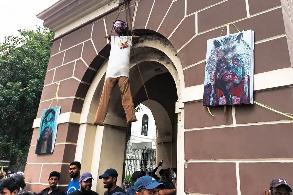 Los activistas se paran debajo de una efigie del presidente de Sri Lanka, Gotabaya Rajapaksa, que cuelga de una torre de reloj cerca de su residencia oficial, en Colombo. Los manifestantes de Sri Lanka se negaron a moverse de la residencia del presidente Gotabaya Rajapaksa el 10 de julio, un día después de que asaltaron su hogar, lo que lo obligó a huir con la marina y anunciar que renunciaría.