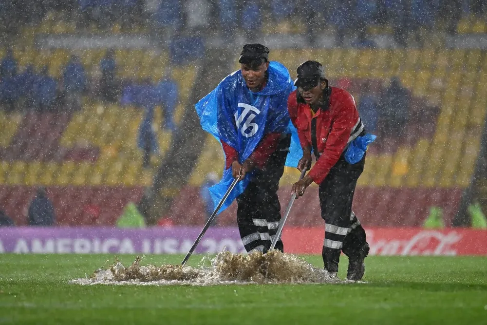 Con lampazos intentan retirar el agua de la cancha, mientras sigue lloviendo en el Campín de Bogotá en Millonarios vs Peñarol por la Copa Sudamericana