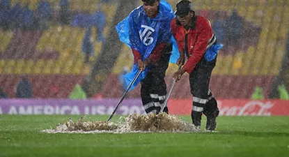 Con lampazos intentan retirar el agua de la cancha, mientras sigue lloviendo en el Campín de Bogotá en Millonarios vs Peñarol por la Copa Sudamericana