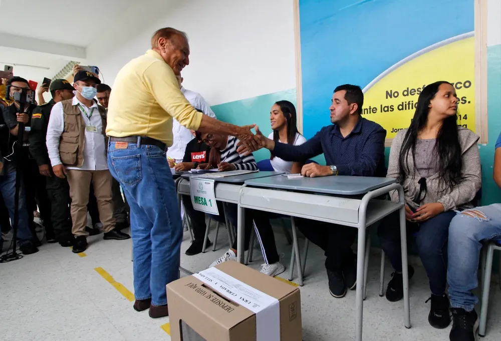 El candidato presidencial independiente colombiano Rodolfo Hernández le da la mano a un hombre que preside el colegio electoral en Bucaramanga, Colombia