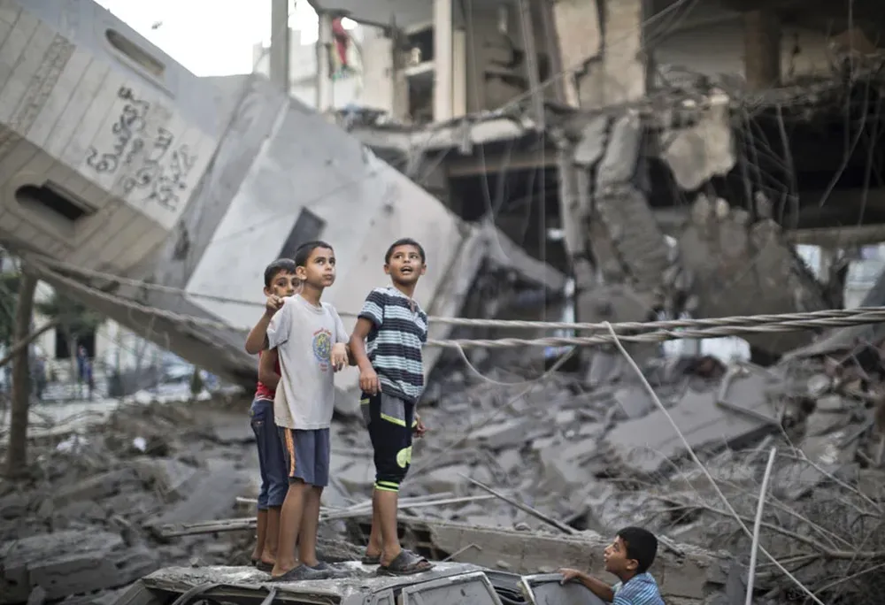 Niños en los escombros de una mezquita derribada en Gaza por bombardeos.