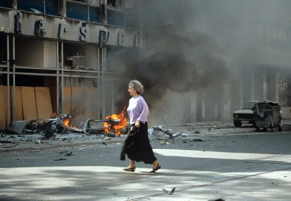 Una mujer corre ante un edificio bombardeado en Sarajevo. EFE/ Archivo  