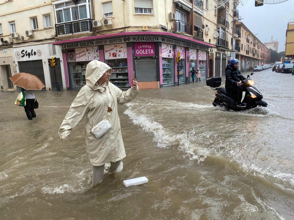 Una mujer hace fotos con el agua hasta las rodillas en una calle de Málaga. EFE