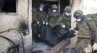 Soldados israelíes recogen cadáveres en el kibutz Kfar Asa.