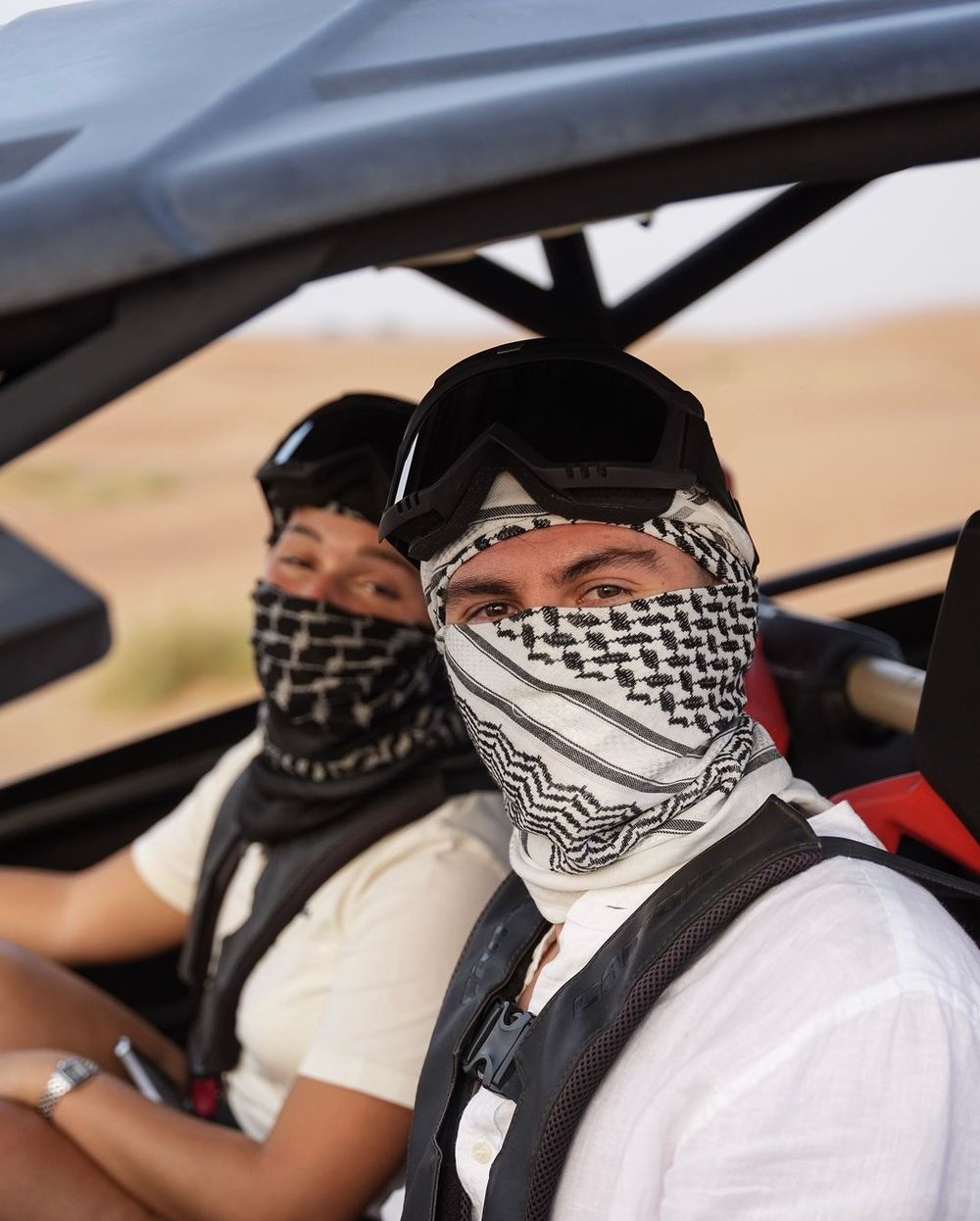 Facundo Pellistri con la cara tapada por el calor, al volante de un buggie y junto a su pareja en el desierto de Dub&aacute;i