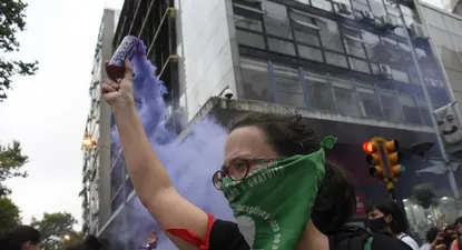Una mujer deja salir humo violenta durante la marcha del 8 de marzo