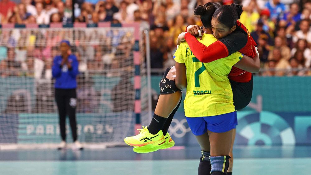Tamires Araujo de Brasil lleva en brazos a su rival Albertina Kassoma de Angola, durante un partido de balonmano en París 2024.
